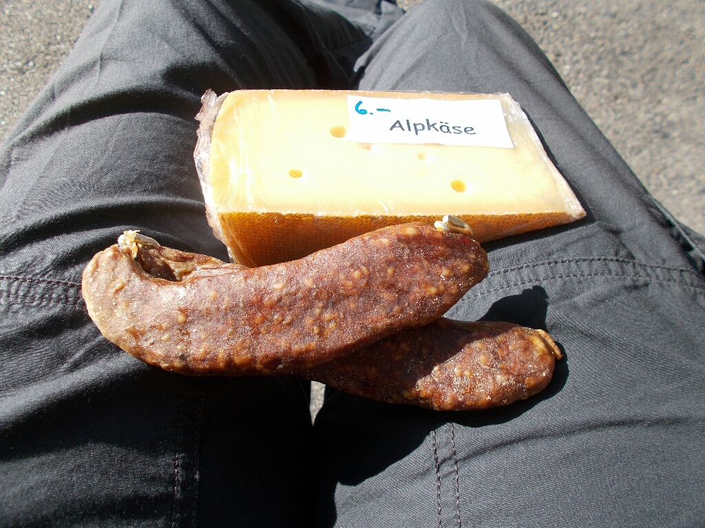 Two links of sausage and a section of a cheese wheel photographed on the author's lap in Disentis, Switzerland.
