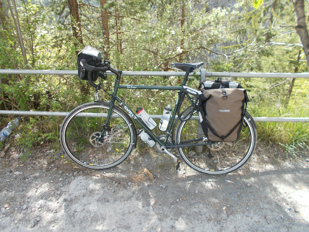 A Surly Disc Trucker fully loaded for touring, leaning against a metal fence.