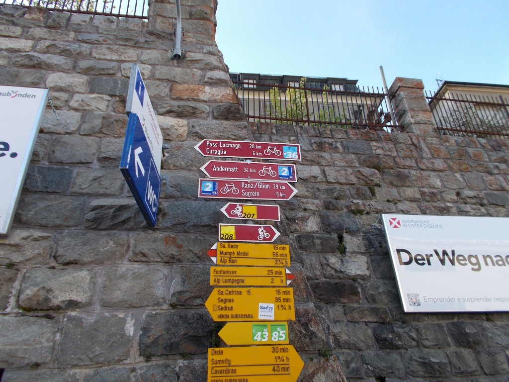 Swiss cycling, hiking, and recreational signposting backed by a rock wall.