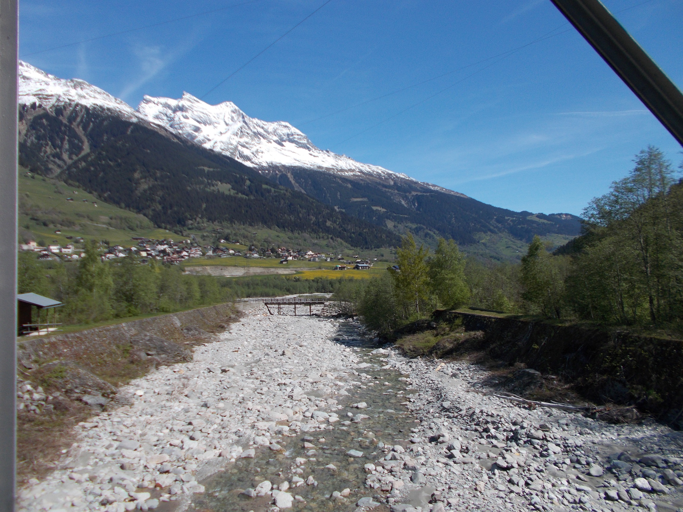 A riverbed with the Rhine running through it. Mountains and a town are visible in the background.