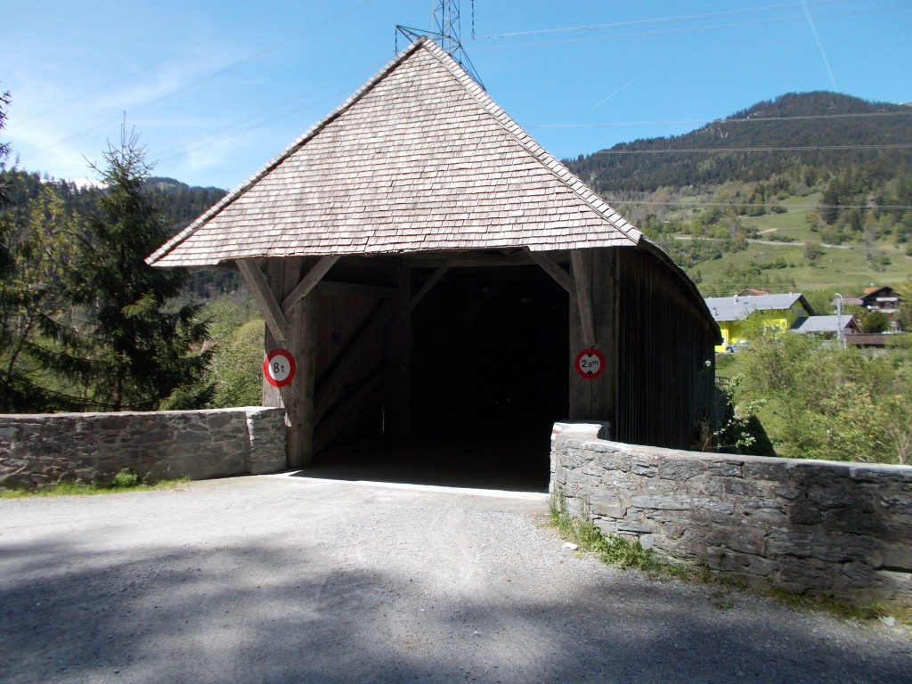 A wooden covered bridge with a town in the background.