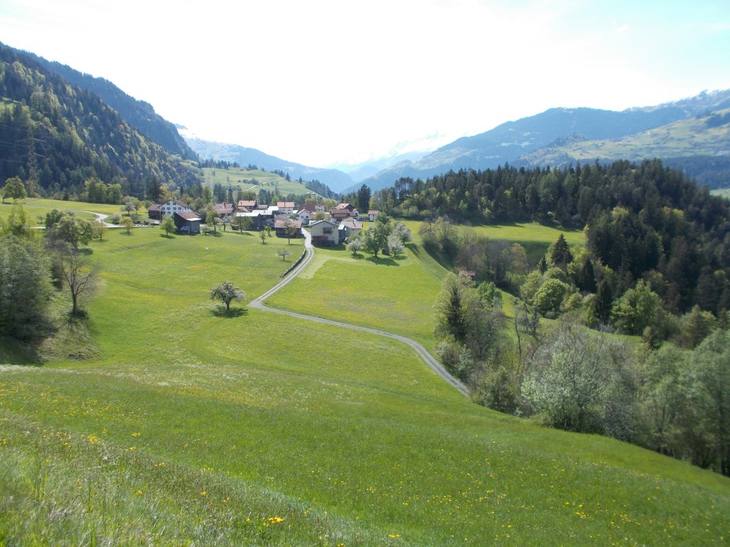 Rolling grass foothills with a village in the background.