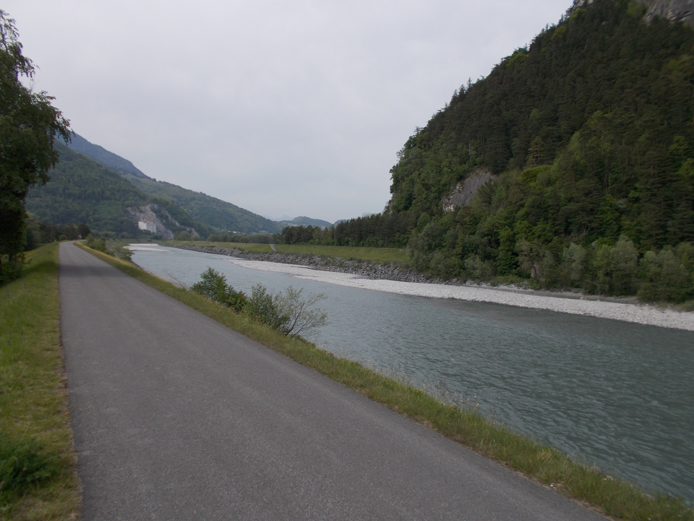 A straight section of bike path bordering the Rhine river in the river valley.