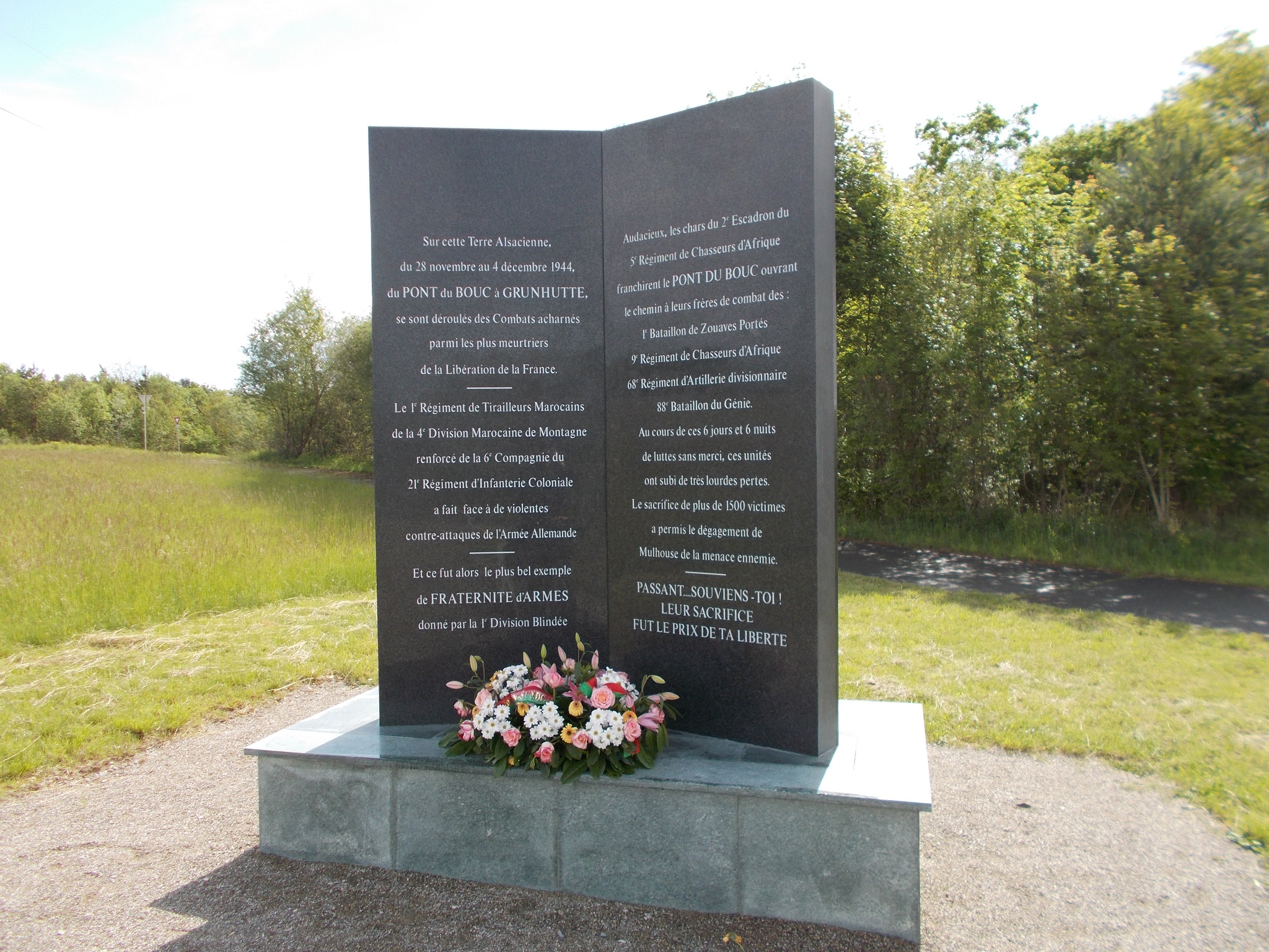 A memorial to fallen soldiers with a path and forest in the background.