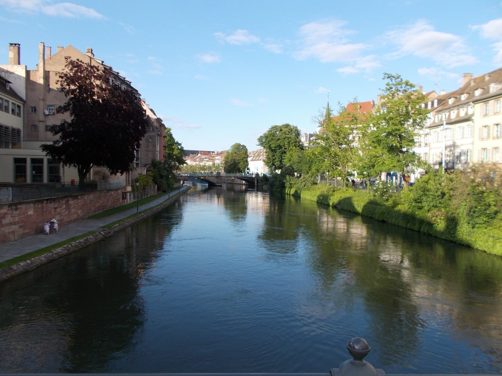 A scenic shot of a large waterway with buildings on either side, a bridge in the distance.